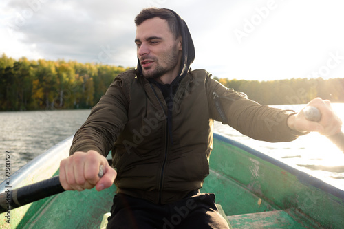 A man rowing on oars on an autumn lake