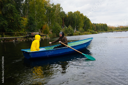 A woman and a man sail on a boat on an autumn lake