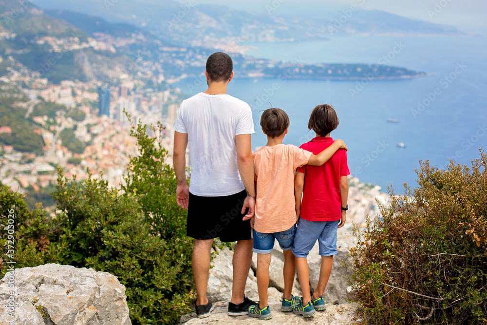 Family, looking at the view of Monaco from La Turbie, standing on top of the rocks in the valley