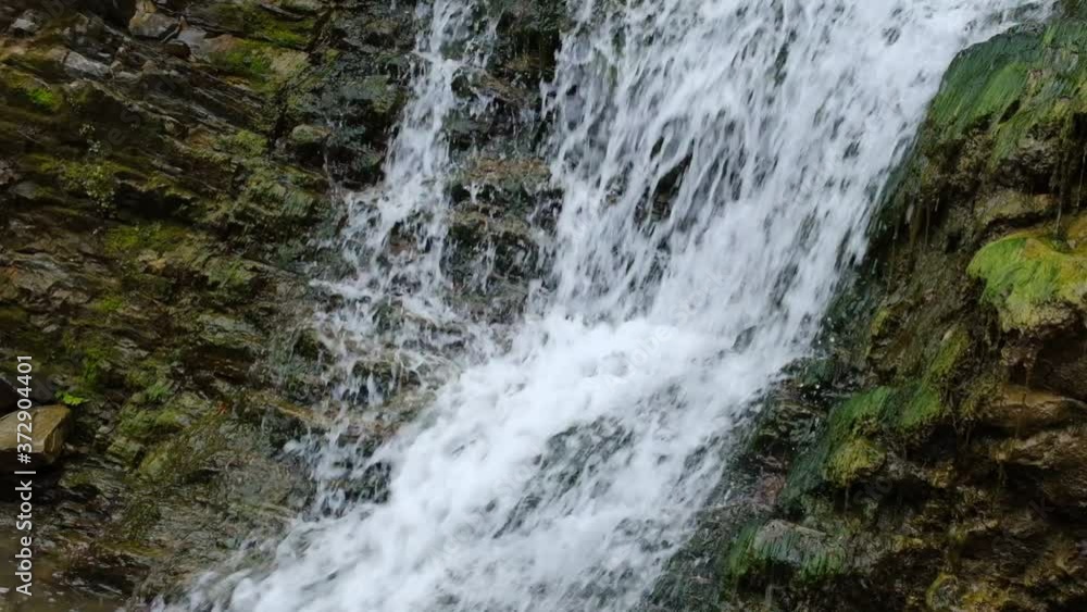 Close up of powerful mountain waterfall stream or river runs down hill. Fresh water in natural stream in national park, protected natural area or reserve. Nature composition. Slow motion Close up of powerful mountain waterfall stream or river runs down hill. Fresh water in natural stream in national park, protected natural area or reserve. Nature composition. Slow motion