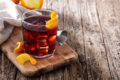 Boulevardier cocktail and orange zest on wooden table. Copy space	 photo