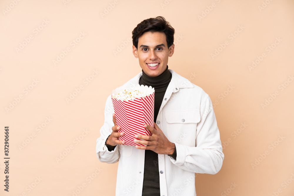 Man over isolated background holding a big bucket of popcorns