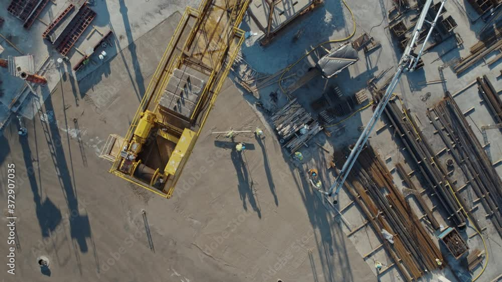 Aerial Flight Over a New Constructions Development Site with High Tower Cranes Building Real Estate. Heavy Machinery and Construction Workers are Employed. Top Down View at Contractors in Safety Hats. Aerial Flight Over a New Constructions Development Site with High Tower Cranes Building Real Estate. Heavy Machinery and Construction Workers are Employed. Top Down View at Contractors in Safety Hats.