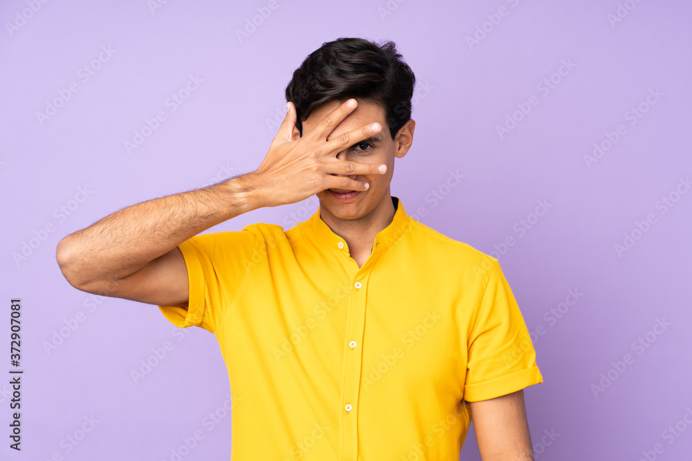 Man over isolated purple background covering eyes by hands and smiling Man over isolated purple background covering eyes by hands and smiling