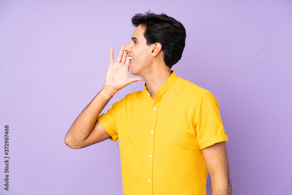Man over isolated purple background shouting with mouth wide open to the lateral Man over isolated purple background shouting with mouth wide open to the lateral