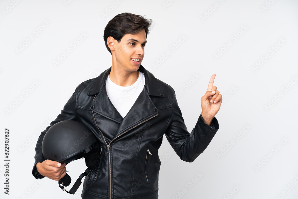 Man holding a motorcycle helmet over isolated white background pointing finger to the side Man holding a motorcycle helmet over isolated white background pointing finger to the side