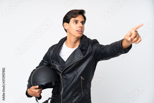 Man holding a motorcycle helmet over isolated white background pointing away