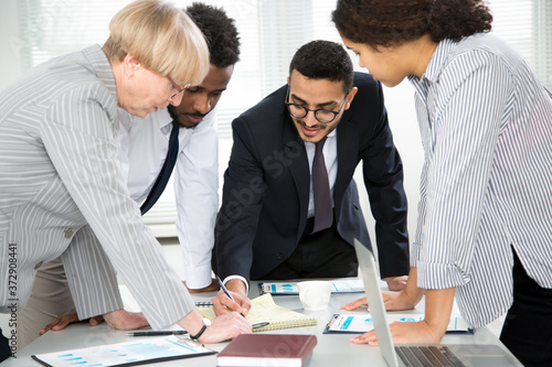 International group of business people working and communicating sitting near office desk.