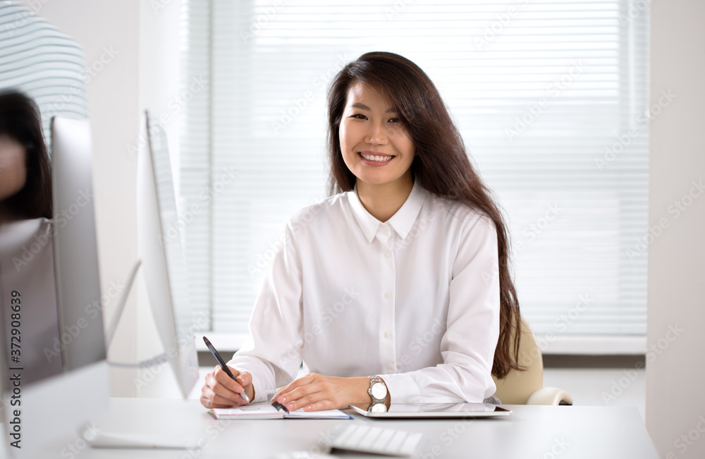 Asian business woman smiling at camera in an office Asian business woman smiling at camera in an office