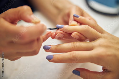 Female hands during manicure procedure in salon