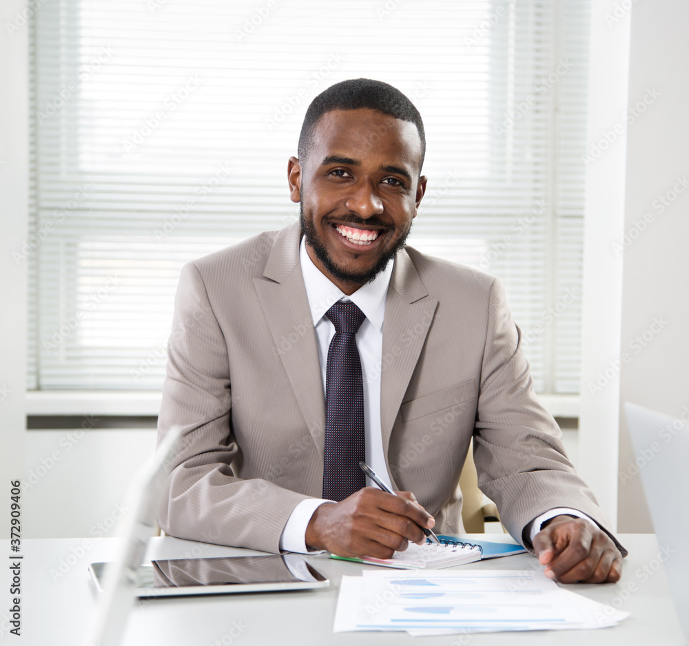 Happy handsome african american businessman smiling while looking at camera in office Happy handsome african american businessman smiling while looking at camera in office