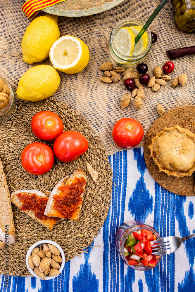 Fototapeta premium Traditional Majorcan food. Typical cuisine of the Balearic Islands. Picnic with fruit, almonds, pastries and sausages. Top view.