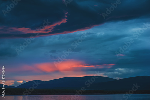 Beautiful mystical sundown in hills with clouds and reflection in the water