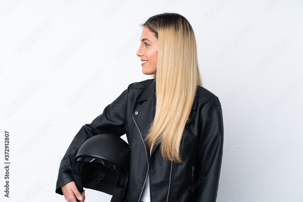 Young Uruguayan woman with a motorcycle helmet over isolated white background looking to the side