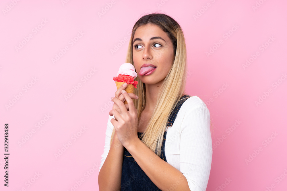 Young Uruguayan woman with a cornet ice cream over isolated pink background Young Uruguayan woman with a cornet ice cream over isolated pink background
