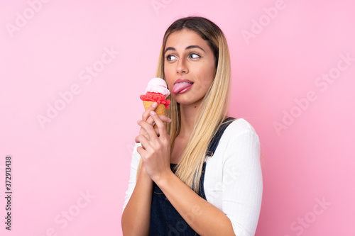 Young Uruguayan woman with a cornet ice cream over isolated pink background