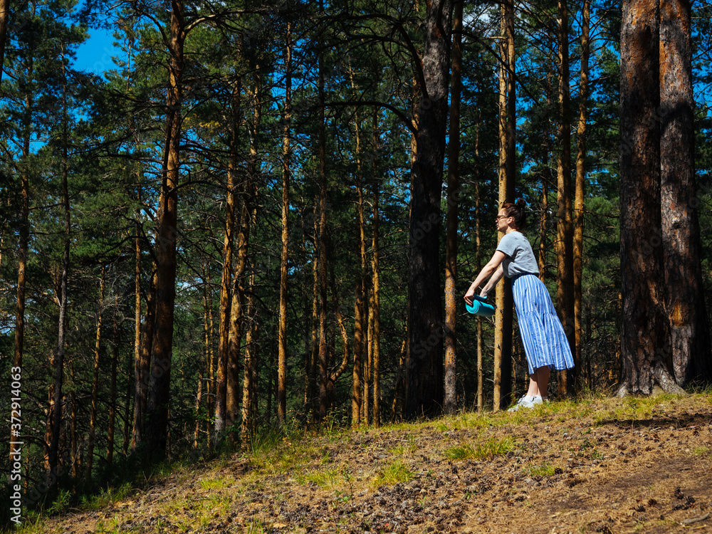 A young woman unwraps a bright yoga Mat in the forest, copy space, Sunny weather, summer. The girl is preparing for practice and meditation in the open air. Outdoor sports, Hiking, healthy lifestyle A young woman unwraps a bright yoga Mat in the forest, copy space, Sunny weather, summer. The girl is preparing for practice and meditation in the open air. Outdoor sports, Hiking, healthy lifestyle