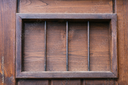 Dark colored wooden background with window with iron bars
