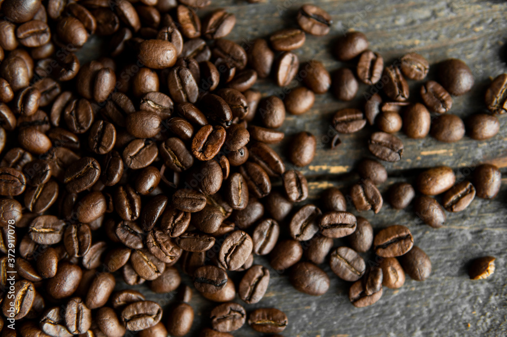 Roasted arabica coffee beans scattered on a wooden table. Fresh coffee beans. Roasted arabica coffee beans scattered on a wooden table. Fresh coffee beans.