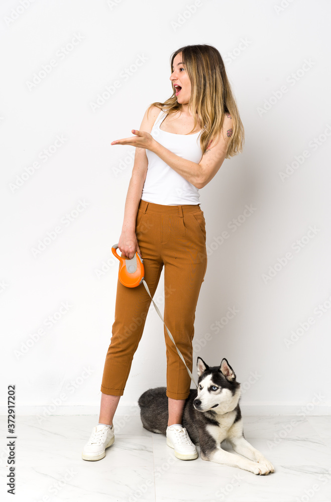 A full length young pretty woman with her dog with surprise facial expression