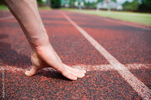 A starting position of a sprinter on a running track, close-up on hand.