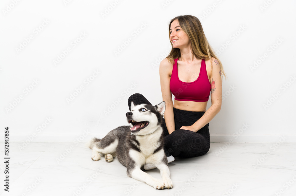 Young sport girl with her dog sitting on the floor looking side