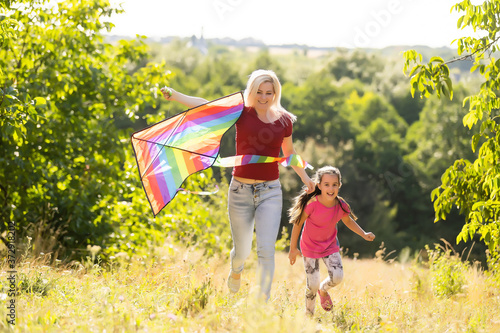 happy family mother and child run on meadow with a kite in the summer on the nature © Angelov