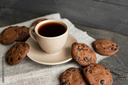 Coffee cup with cookies on wooden table background. Mug of black coffee with chocolate cookies. Fresh coffee beans.