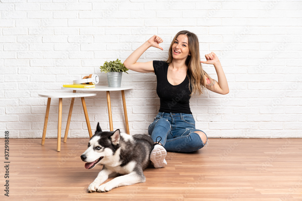Young pretty woman with her husky dog sitting in the floor at indoors proud and self-satisfied Young pretty woman with her husky dog sitting in the floor at indoors proud and self-satisfied