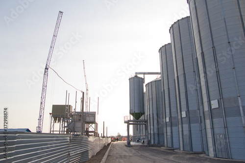 Construction of a feed mill agro-processing plant for processing and silos for drying cleaning and storage of agricultural products  flour  cereals and grain.  Silver tanks close-up.