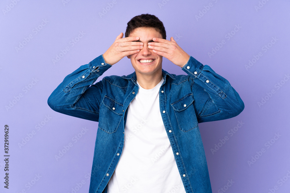 Teenager caucasian handsome man isolated on purple background covering eyes by hands Teenager caucasian handsome man isolated on purple background covering eyes by hands