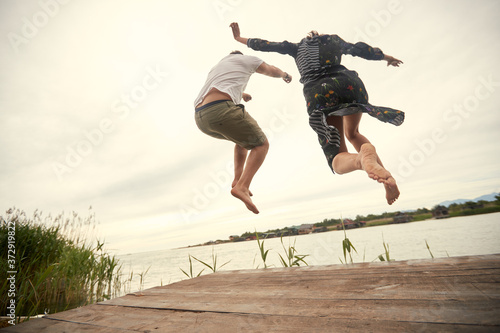 Young couple jumping on the shore of the lake