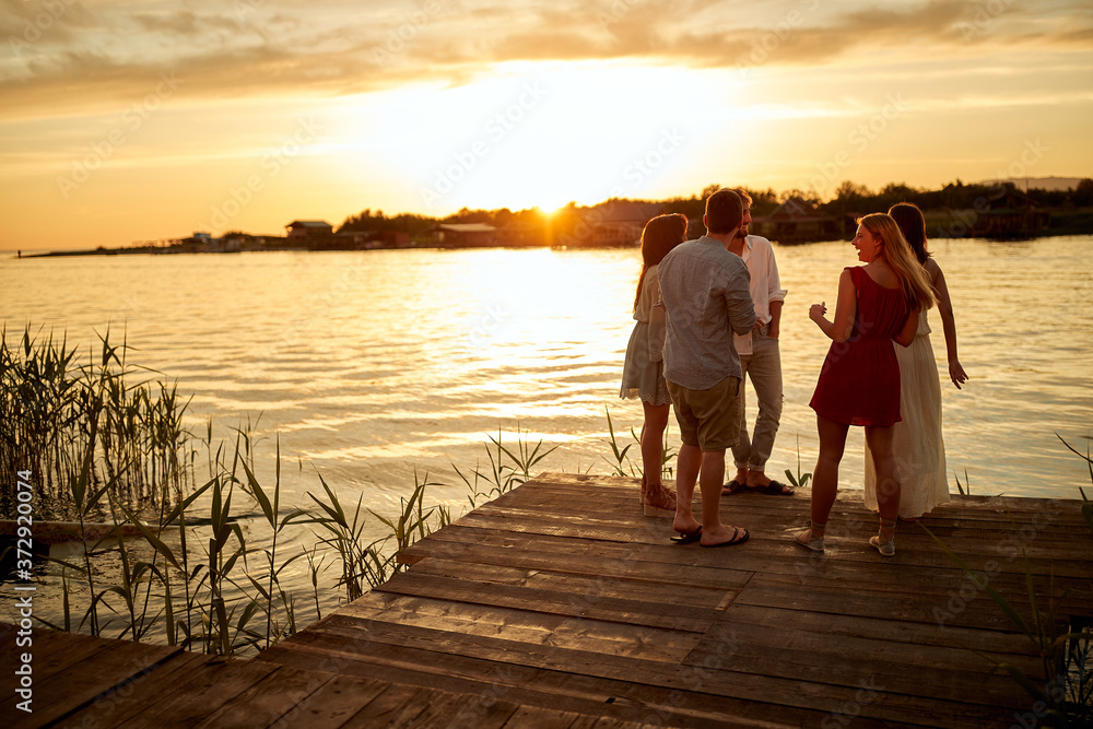 Fototapeta premium Group of friends enjoying the sunset on the lake