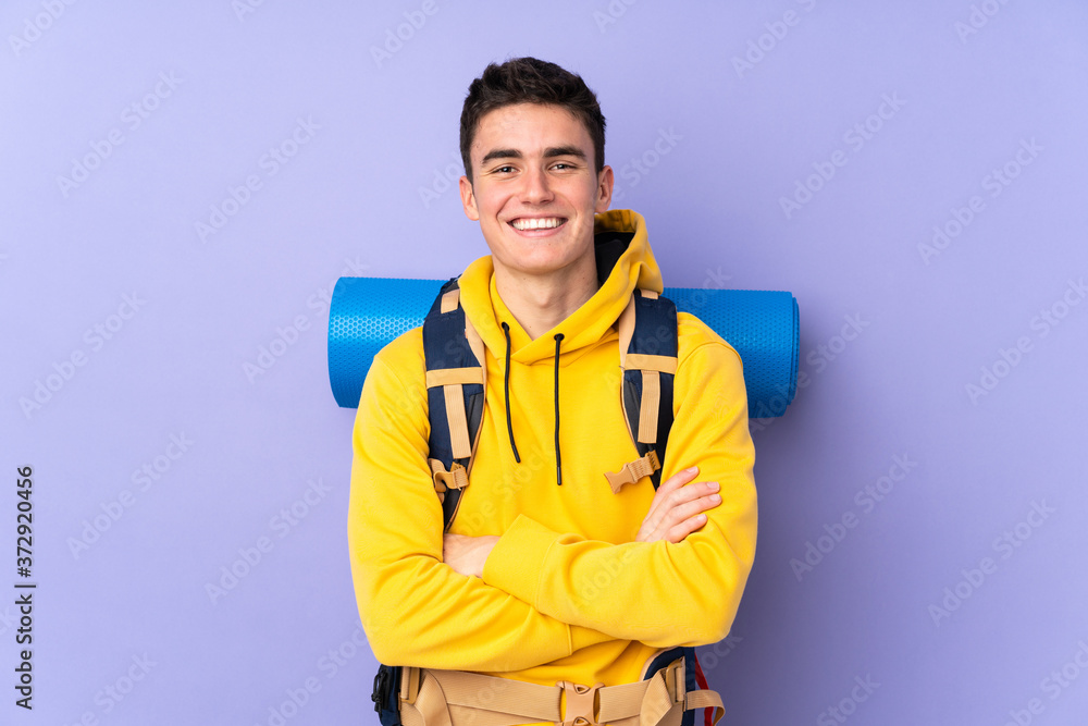 Teenager caucasian mountaineer man with a big backpack isolated on purple background laughing Teenager caucasian mountaineer man with a big backpack isolated on purple background laughing