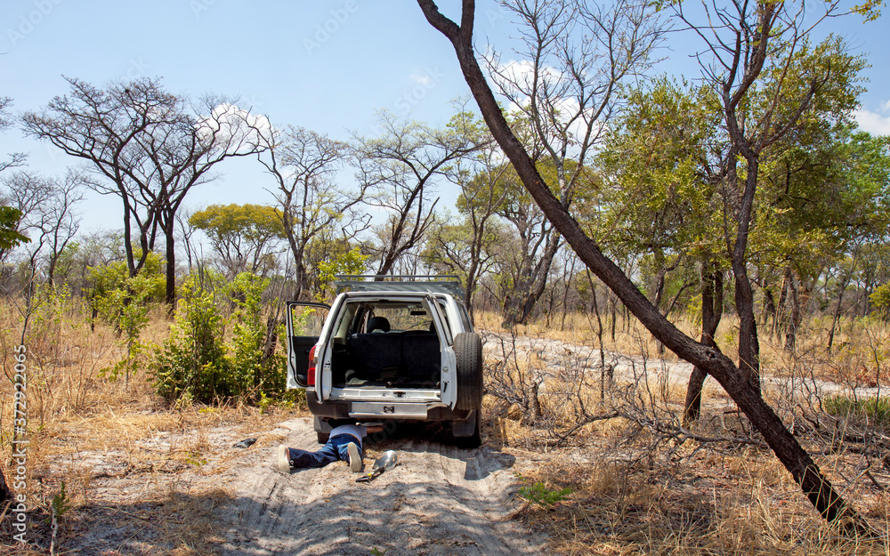 Rundu, Namibia: a man lies under a 4x4 car on a dirt road in the middle of the bush, to see what the problem is.