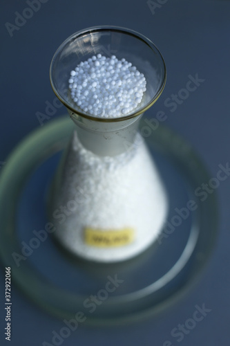 Loose white ammonium nitrate in the form of fine granules, in a conical flask.