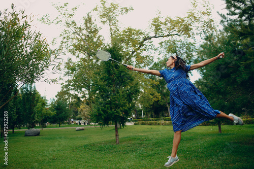 Young adult woman playing badminton in the park. With motion blur.