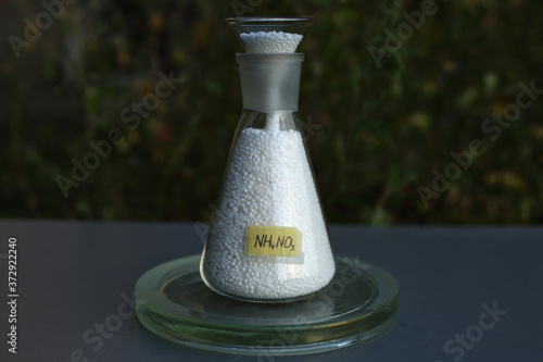 Full conical flask of white spherical ammonium nitrate, with a funnel for free-flowing substances, and a formula. photo