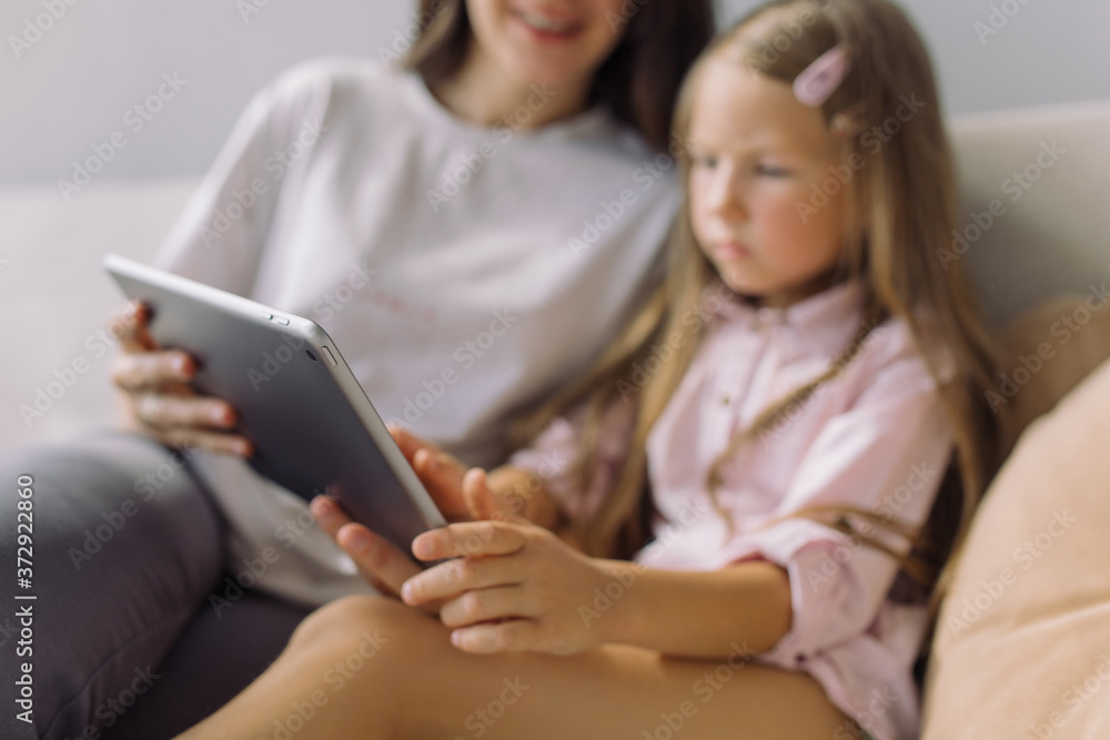 Nanny showing educational cartoon on tablet to little girl. Focus on technology. Nanny showing educational cartoon on tablet to little girl. Focus on technology.