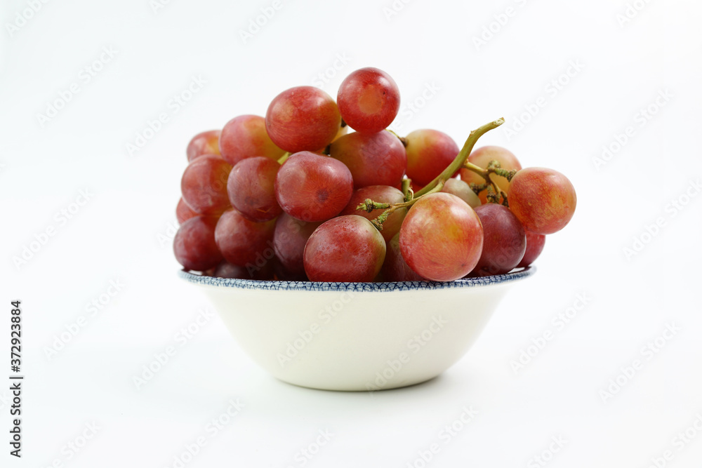 A bowl of red grapes on the vine, isolated on a white background A bowl of red grapes on the vine, isolated on a white background