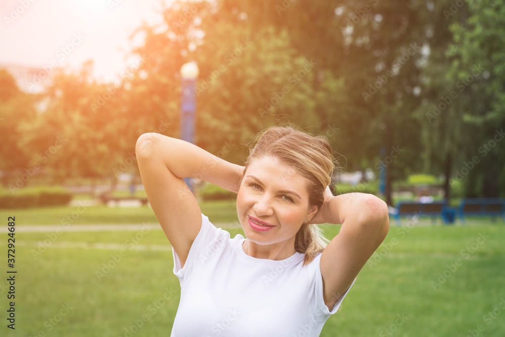 Image of beautiful middle-aged woman laughing in summer park