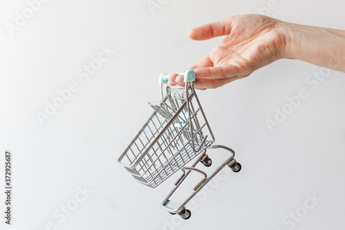 Female hand with empty toy shopping cart over white background.
