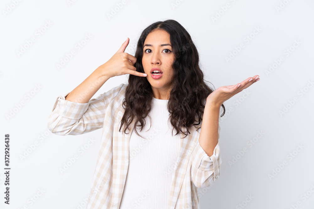 Mixed race woman over isolated white background making phone gesture and doubting Mixed race woman over isolated white background making phone gesture and doubting