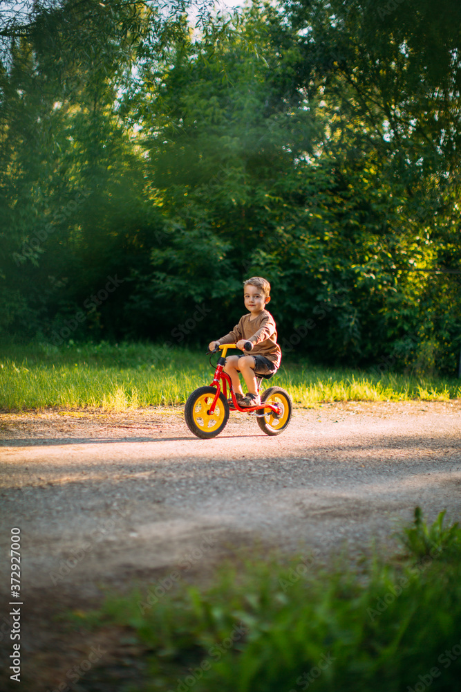 Cute little boy rides a bicycle on a path in nature. Learning to ride a bicycle. Summer walks