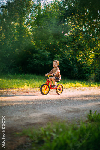 Cute little boy rides a bicycle on a path in nature. Learning to ride a bicycle. Summer walks