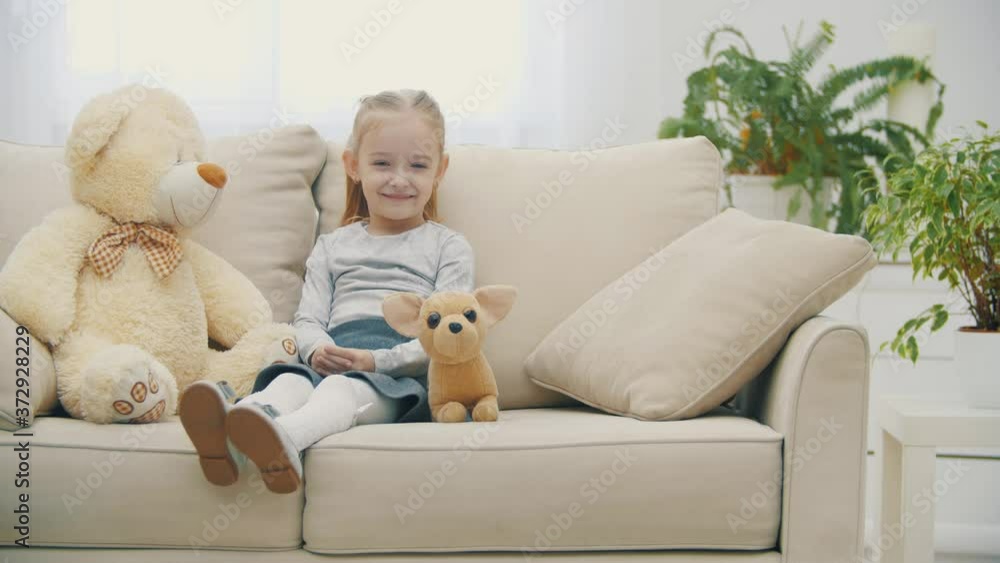 4k slowmotion video of little cute girl sitting on white sofa. 4k slowmotion video of little cute girl sitting on white sofa.