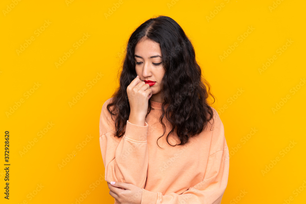 Spanish Chinese woman over isolated yellow background having doubts Spanish Chinese woman over isolated yellow background having doubts
