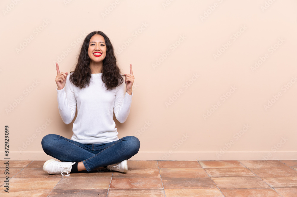 Young woman sitting on the floor pointing up a great idea