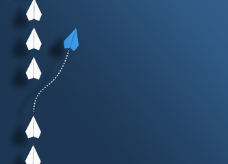paper planes in a row on blue background and one paper glider going in different direction, breaking new ground and stepping out of the line concept
