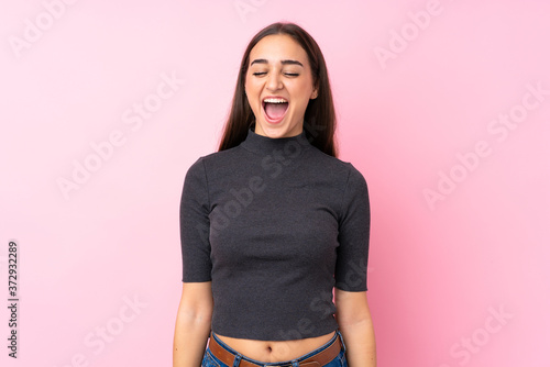 Young girl over isolated pink background shouting to the front with mouth wide open